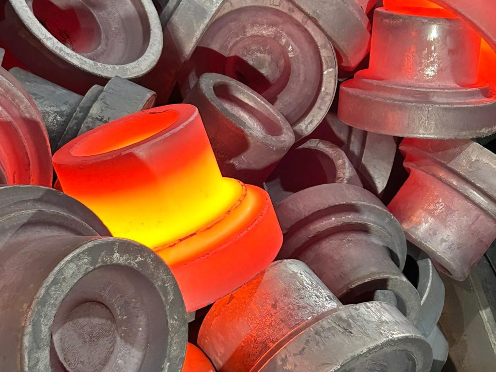 A heated metal piece being hammered into shape during the forging process.